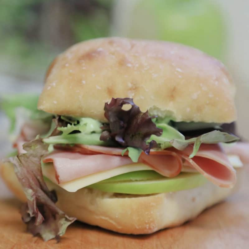 Ham and Swiss Ciabatta Sandwich with Garlic Aioli on a wood board