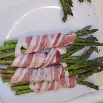 Bacon Wrapped Asparagus on a white plate before cooking