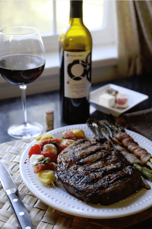 Steak next to bacon wrapped asparagus and caprese salad