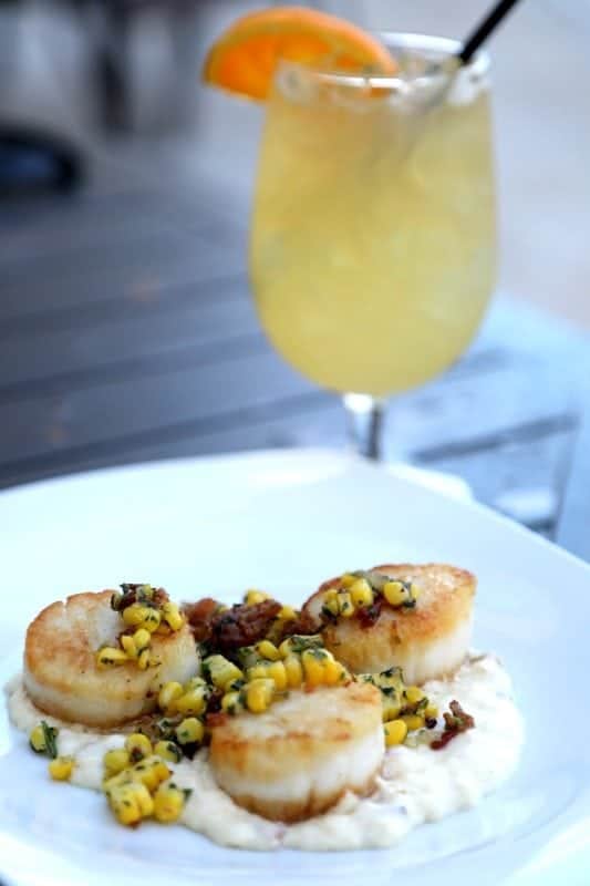 scallops over risotto next to a cocktail