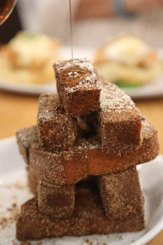 French toast sticks with syrup pouring over them. 