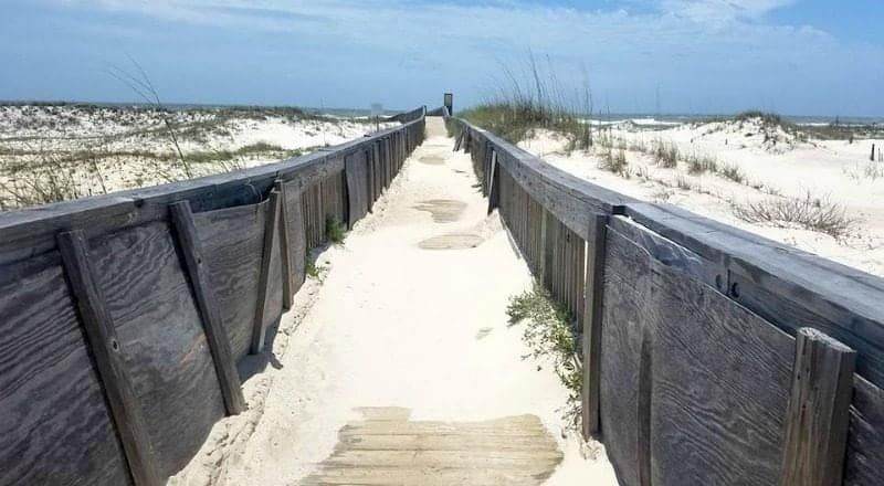 Sand covered walkway leading through sand dunes