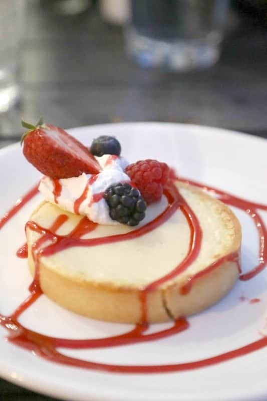 Key lime tart with fresh berries and whipped cream on a white plate