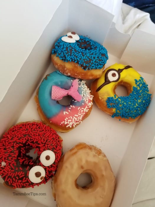 Box of doughnuts including a minions donut and cookie monster donut. 