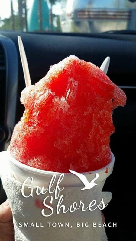 Shave ice in a white cup with a gulf shores logo over the photo