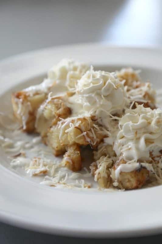 Coconut bread pudding with whipped cream on a white plate