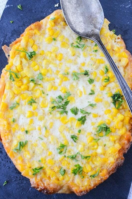 Close up of Crockpot Corn Pudding with a spoon over it