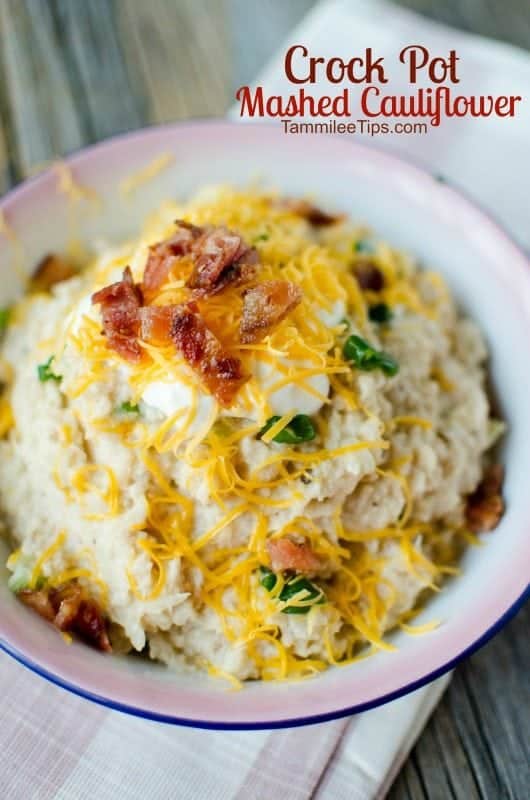 Crock Pot Mashed Cauliflower recipe text written over a bowl of crock pot cauliflower topped with cheddar cheese, bacon, and green onions