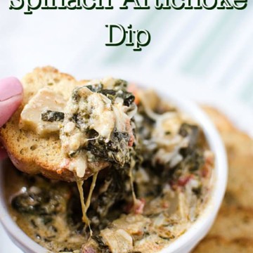 Slow Cooker Spinach Artichoke Dip over a white bowl with a piece of bread covered in cheesy dip