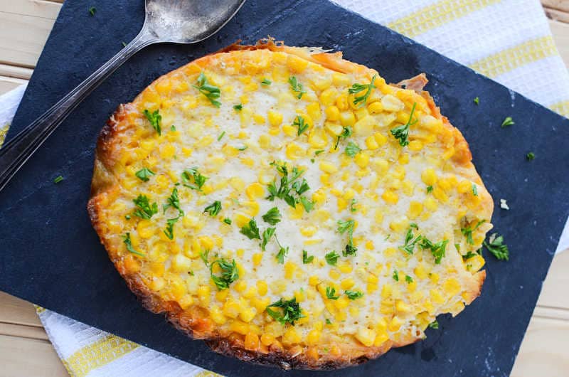 crockpot corn pudding on a blue placemat with a spoon