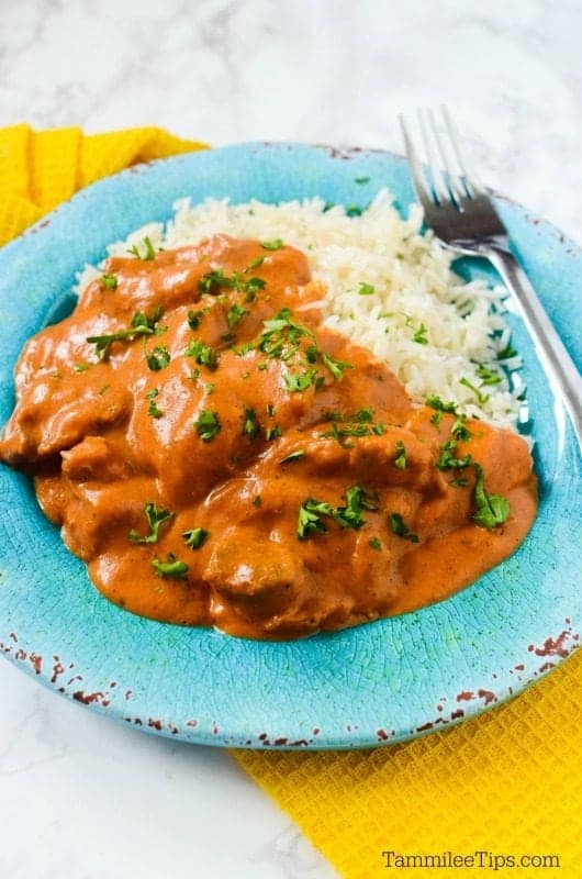  blue plate with chicken tikka masala , white rice, and a fork