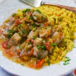 a white plate with Crockpot Pork Chili Verde and rice near a fork