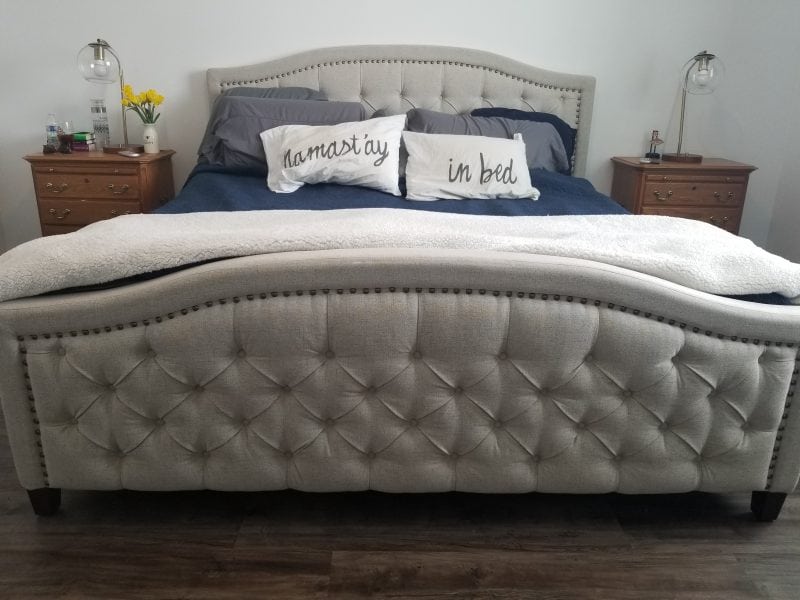 Bed made with comforters next to two nightstands with flower's and lamps on them. 