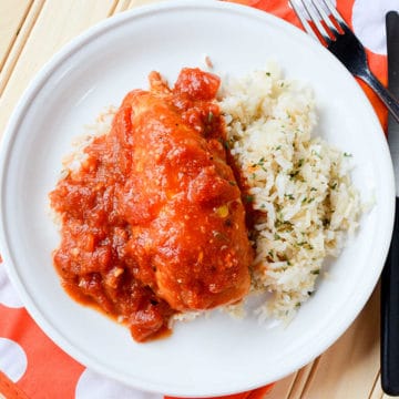 tex mex chicken next to white rice on a white plate with a fork next to it