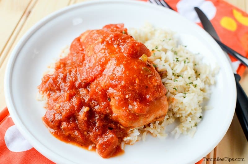 Tex-mex chicken with rice on a white plate next to a fork