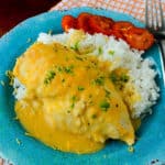 cheesy chicken and rice next to tomatoes on a blue plate with a fork