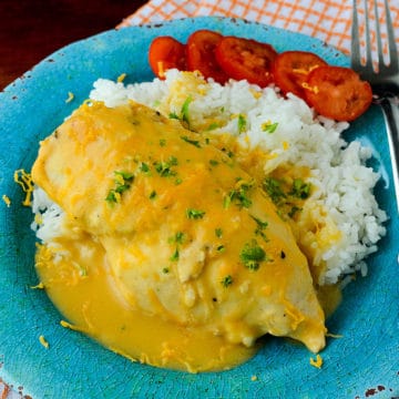 cheesy chicken and rice next to tomatoes on a blue plate with a fork