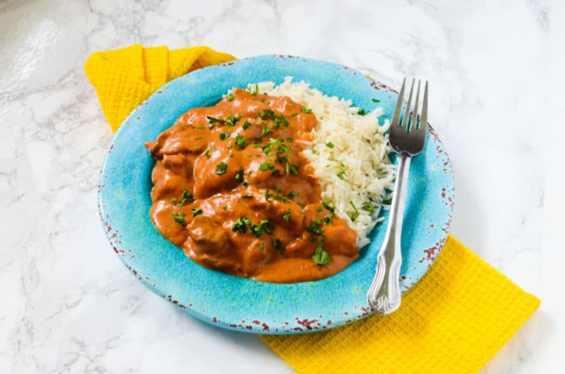  blue plate with chicken tikka masala, white rice, and a fork