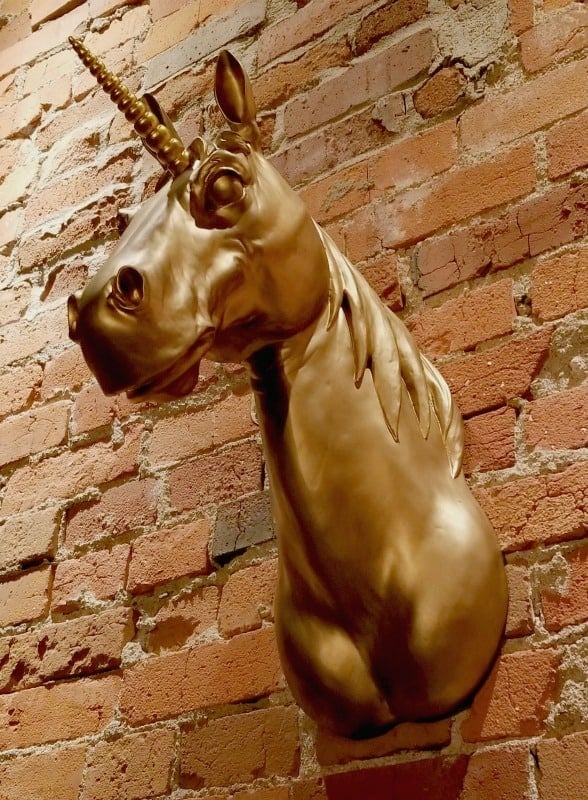 Gold Unicorn head on a brick wall