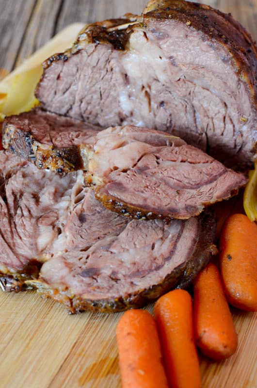 Slices of roast on a cutting board with mini carrots