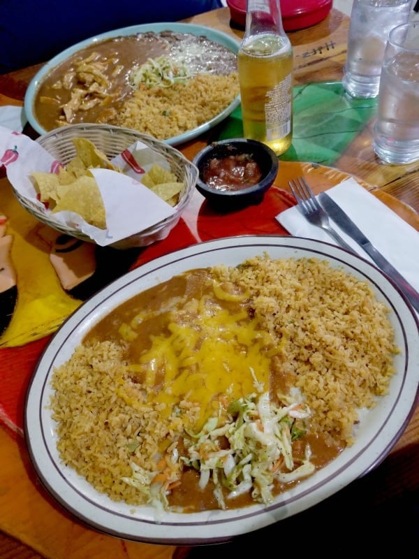 Cheese enchiladas with rice next to chips and salsa and a drink