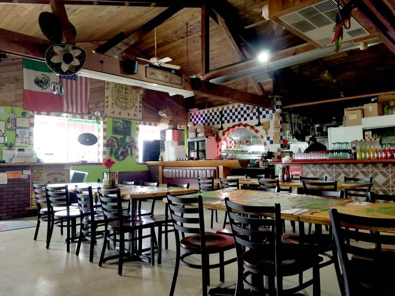 Tables and chairs near a Mexican Flag and restaurant signs