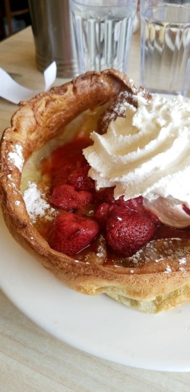 Dutch baby with strawberries and whipped cream on a white plate