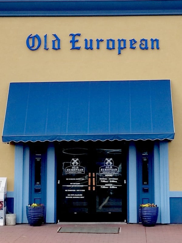 Old European sign over a blue awning and entrance sign