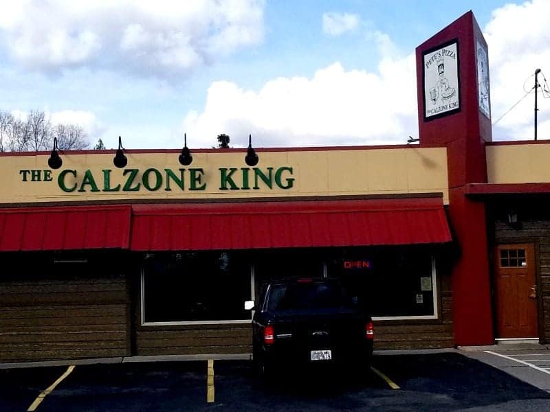 The Calzone King sign over a red awning with a truck parked and Pete's Pizza sign