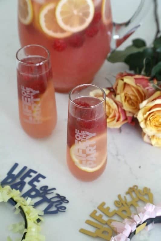 Life of the Party glasses with punch next to roses and a pitcher with raspberries and lemon slices. 