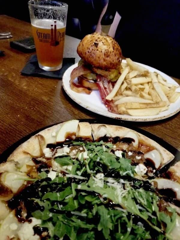 pizza on a plate next to a burger and beer