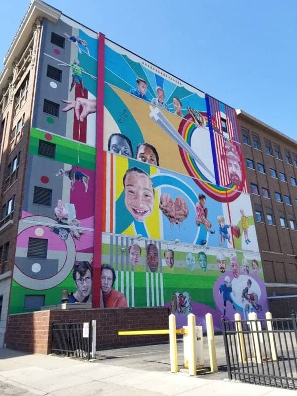 colorful mural with kids on it on the side of a buildling