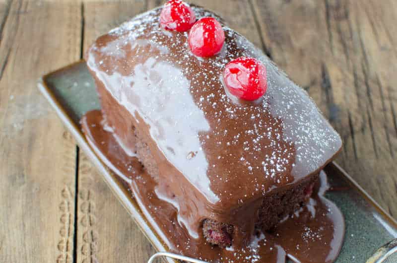 Mini black forest cake on a small tray with cherries on top of it