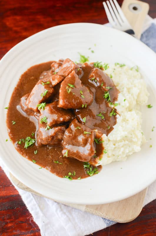 Beef Tips and Gravy on a white plate next to mashed potatoes