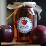 Crock Pot Apple Pie Moonshine in a mason jar next to red apples