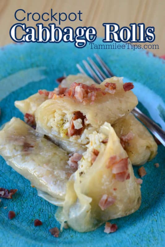 Cabbage rolls garnished with bacon on a blue plate next to a silver fork