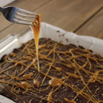 Salted Caramel Rice Krispie Treat in a parchment lined paper with a fork dripping in caramel