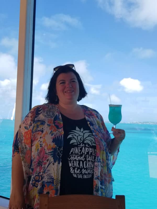Tammilee holding a blue margarita with the ocean in the background