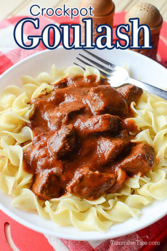 crockpot goulash over a white plate with goulash over egg noodles and a silver fork. 