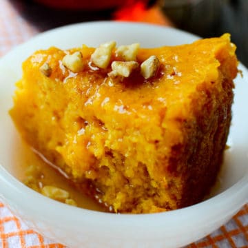 Slice of Crockpot Pumpkin Dump Cake in a white bowl topped with nuts