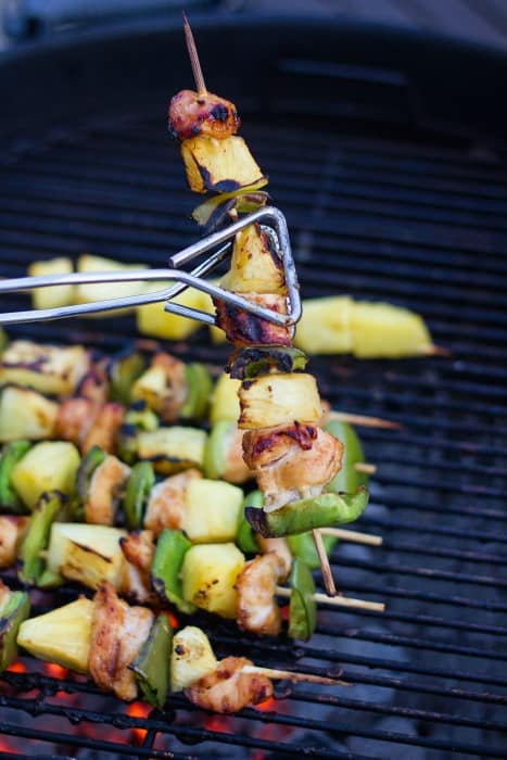 Grilled chicken skewers on a charcoal grill with pineapple and green pepper