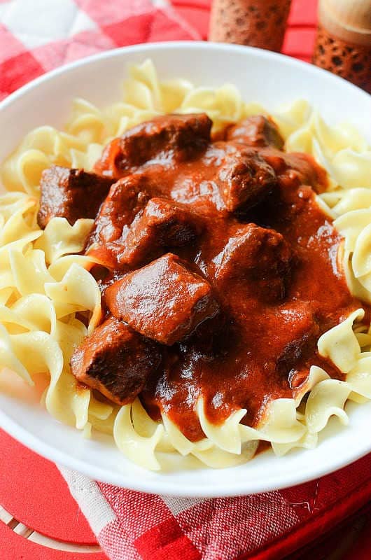 crockpot goulash on a white plate with egg noodles