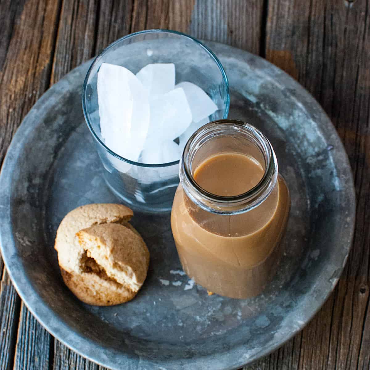 Starbucks Frappuccino copycat in a glass bottle next to a cup of ice and cookies