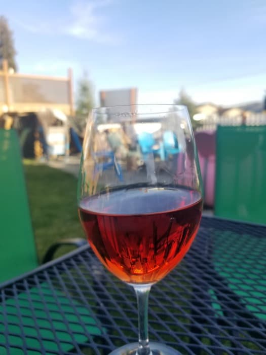 Wine glass with red wine on a dark table next to green chairs