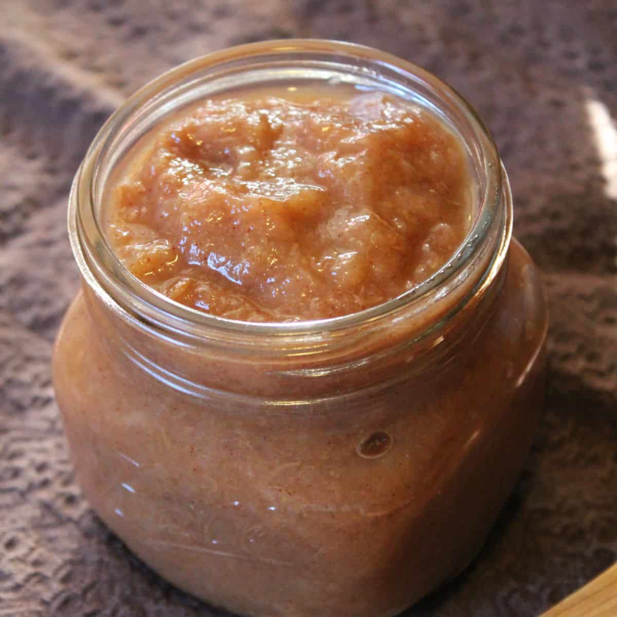 Crockpot pear butter in a glass mason jar on a brown napkin
