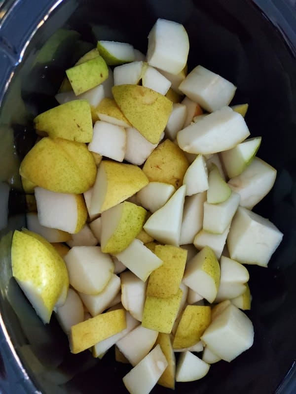 pears cut into pieces in a dark slow cooker bowl 