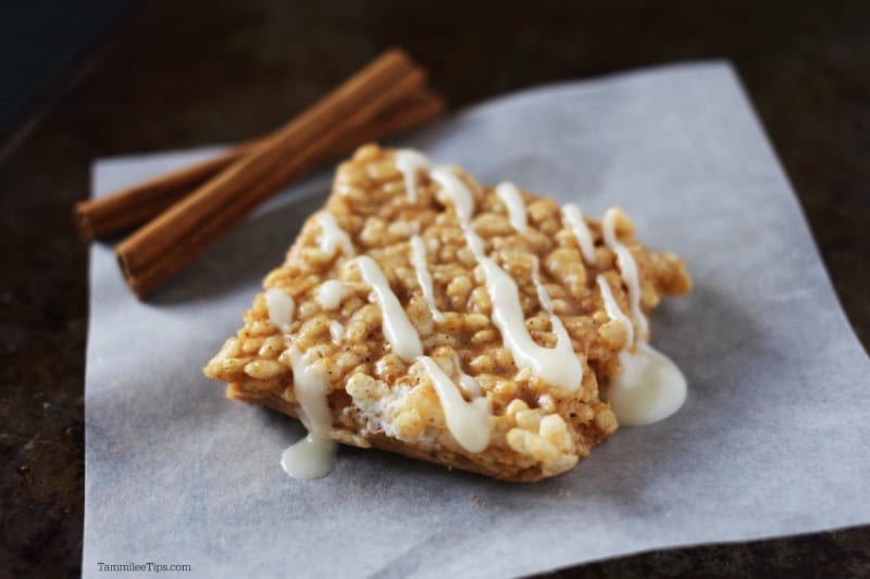 Pumpkin Spice Rice Krispie Treats on parchment paper with cinnamon sticks behind 