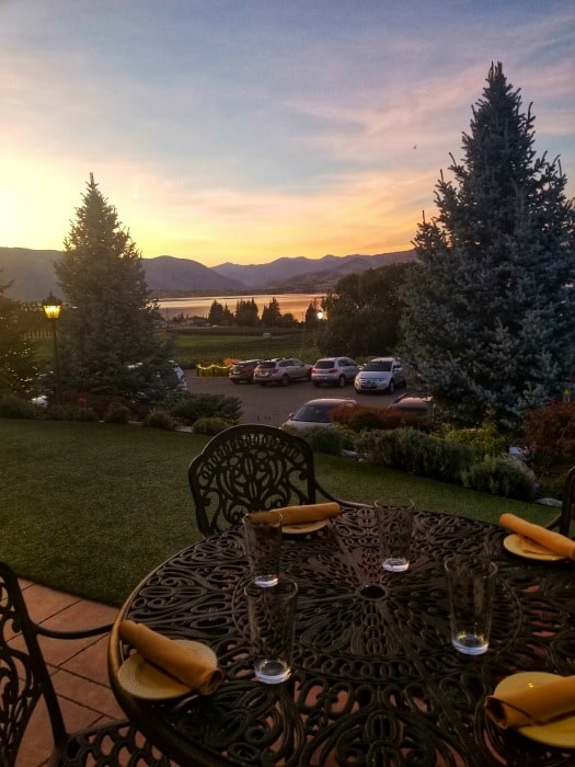 Sunset over the lake from a table with chairs, place settings, and a view of the parking lot and rolling hills