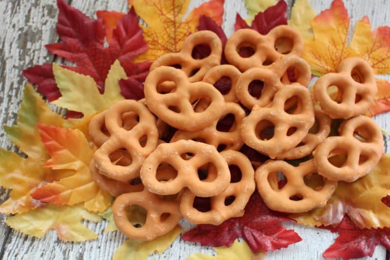 pumpkin spice pretzels spread among fake leaves on a wood background