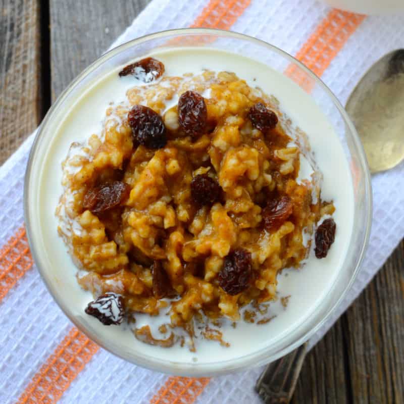 Crock Pot Pumpkin Oatmeal with cream in a glass bowl on a cloth napkin